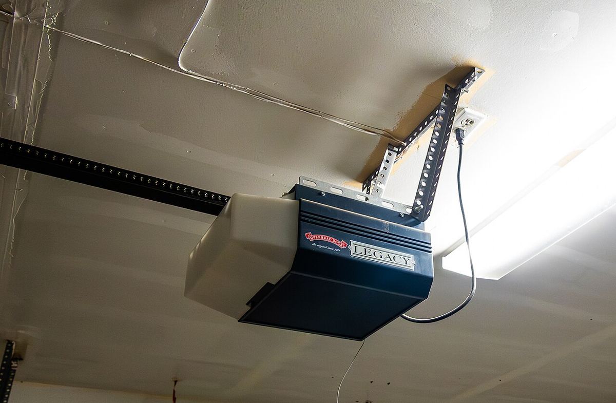 Residential garage door opener with ceiling brackets, rail and power connection visible