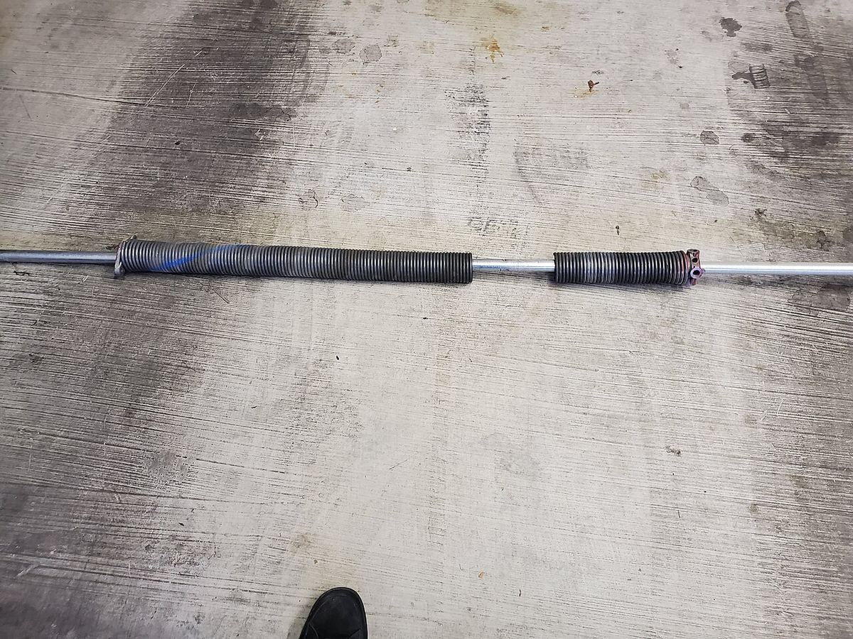 A broken garage door torsion spring on its shaft, photographed after removal